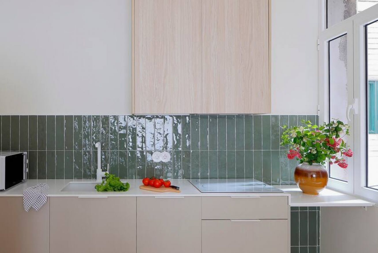 Une cuisine équipée d’un four à micro-ondes, d’un évier, d’une planche à découper avec des tomates et d’un vase rempli de fleurs.