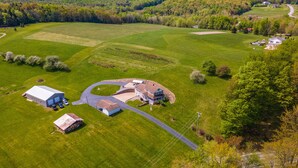 Luchtbeeld van een landgoed met een groot huis, schuren en uitgestrekte groene velden.