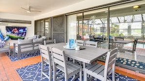 A spacious patio area with a dining table, chairs, and a ceiling fan.