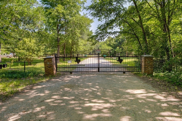 A gated entrance to a park with a gravel path leading through.
