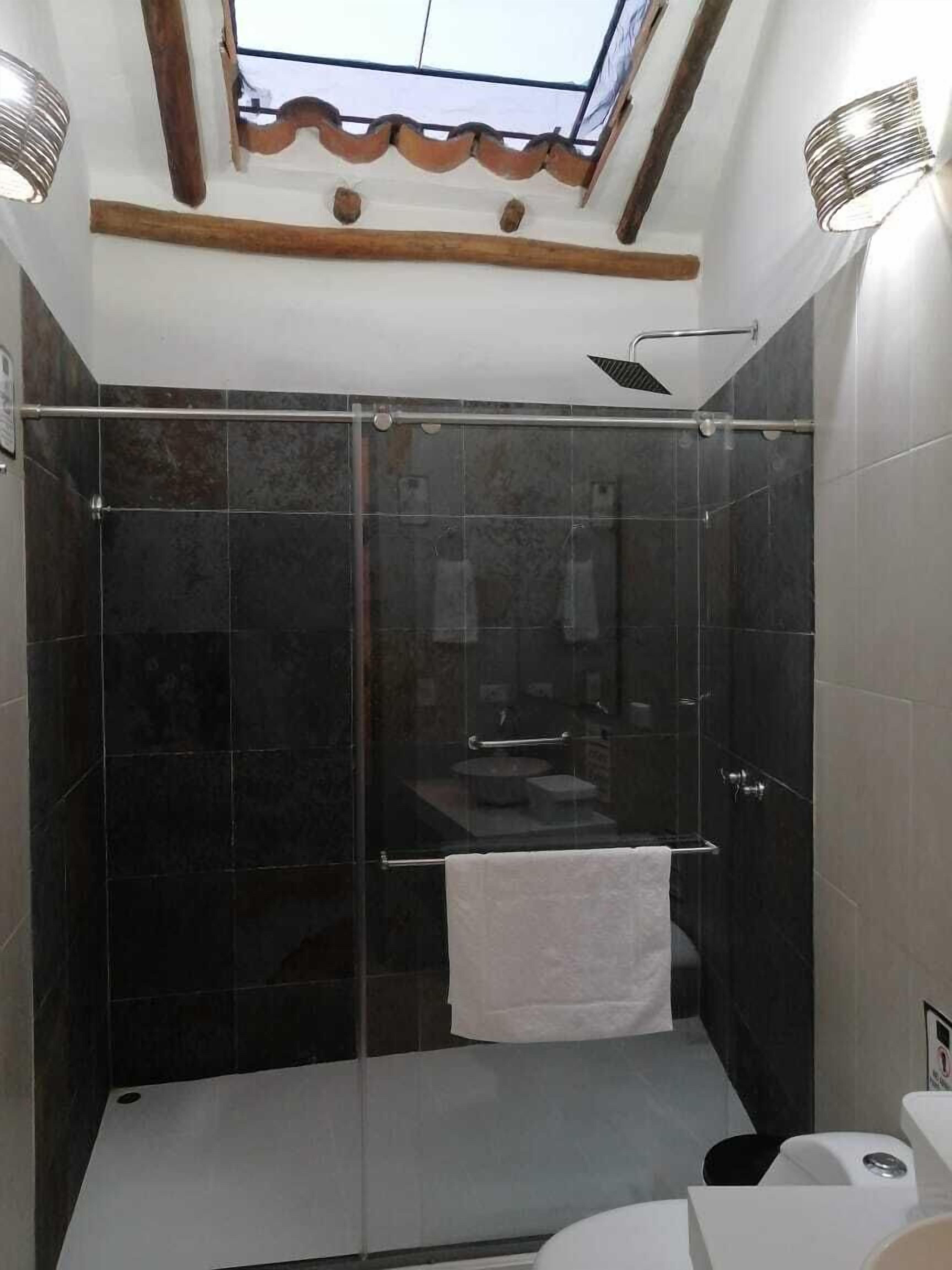 A modern bathroom with a glass-enclosed shower, a white sink, and a towel hanging on the wall.
