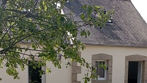 A building with a gravel driveway, a wooden picnic table, and a door. - Le Penty Gîte (Plestin-les-Grèves)