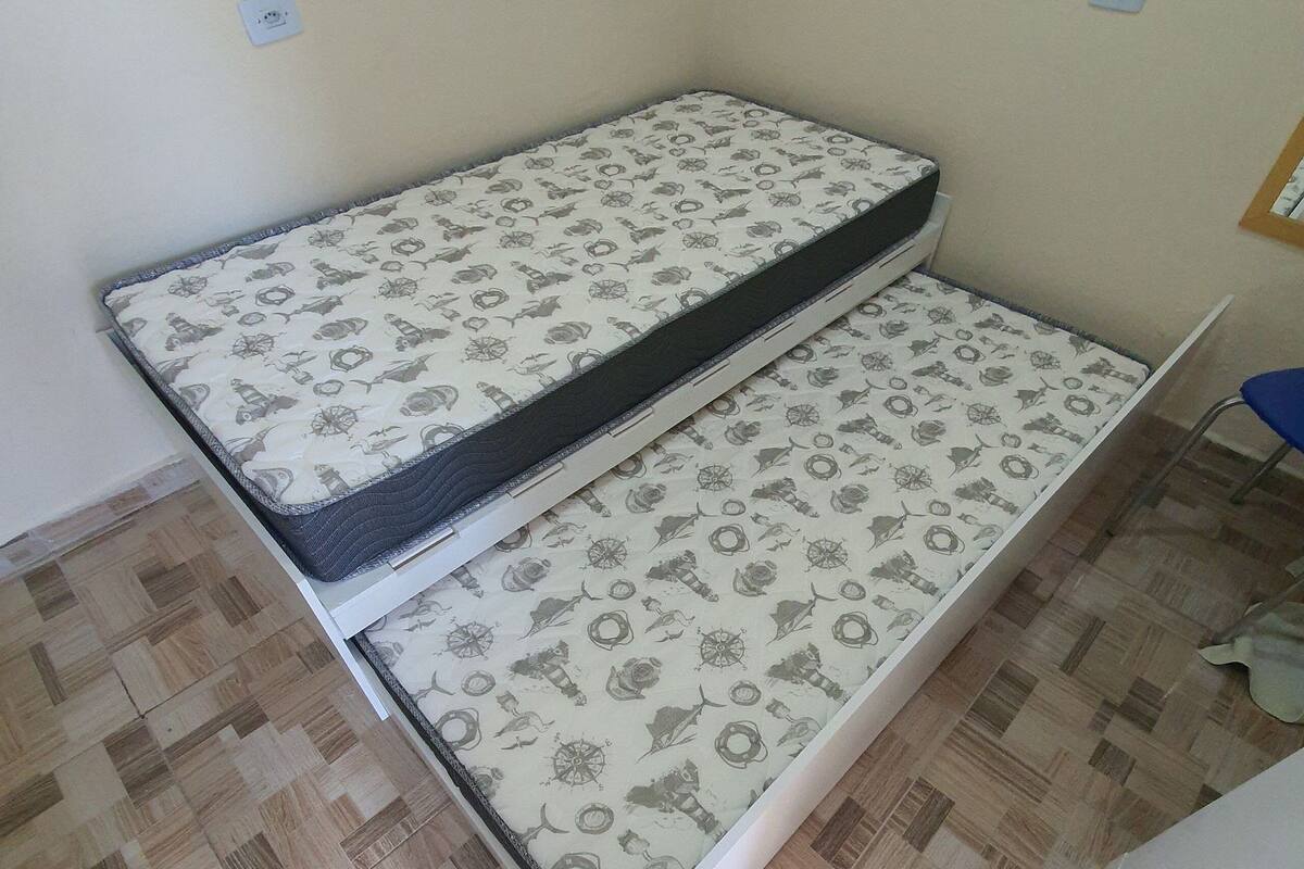 Una habitación con un colchón en el suelo, una silla y una puerta.