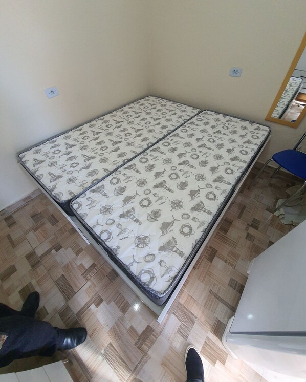 A room with a bed, a blue chair, and a wooden floor.