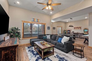 A spacious living area with a sectional sofa, a coffee table, and a ceiling fan. - 8BR IndianPoint Oasis- GolfCart + Sauna + Gym + EV (Branson)