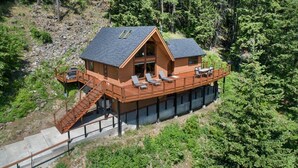 Eine Holzhütte mit einer Terrasse, einer Treppe und Blick auf den umliegenden Wald.