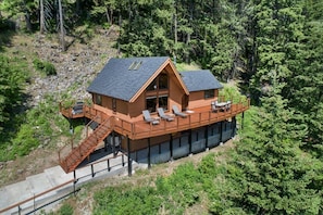 Une cabane en bois dotée d’une terrasse, d’un escalier et offrant une vue sur la forêt environnante.