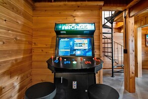 Un intérieur en bois avec une borne d’arcade portant l’inscription « Arcade » et un escalier en colimaçon.