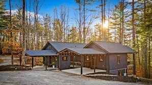 A two-story cabin with a covered porch, a separate garage, and a driveway.
