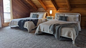 A cozy attic bedroom with two beds, wooden beams, a window, and a nightstand with a lamp. - Access to everything yet secluded and chic, this hideaway has it all. (Davis)