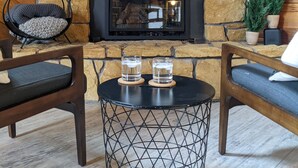 A cozy room with a stone fireplace, two wooden chairs, a round metal table, and a small shelf with a sign. - Access to everything yet secluded and chic, this hideaway has it all. (Davis)
