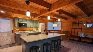 A kitchen with wooden beams, a central island with stools, a stove, and a refrigerator. - Access to everything yet secluded and chic, this hideaway has it all. (Davis)