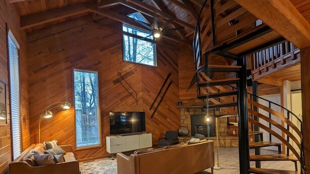 A cozy, wooden interior with a sofa, a coffee table, a TV, and a staircase. - Access to everything yet secluded and chic, this hideaway has it all. (Davis)