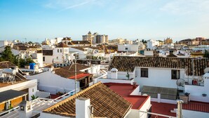 A cityscape with various buildings, including a prominent white building with a red roof and a large, multi-story structure with a dome. - Marbella Village  | Studio with Juliette Balcony (Marbella)