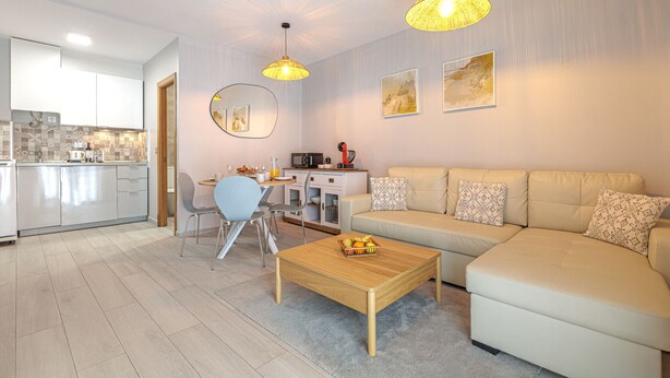 A modern living room with a sofa, coffee table, and dining area.