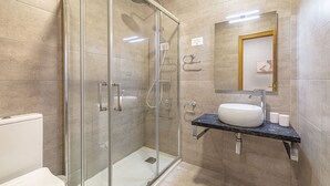 A modern bathroom with a glass-enclosed shower, a white sink, and a marble countertop.