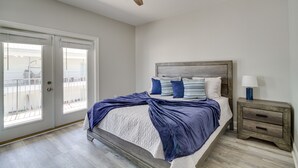 Ein Schlafzimmer mit Bett, Nachttisch, Deckenventilator und Blick durch eine Schiebetür.