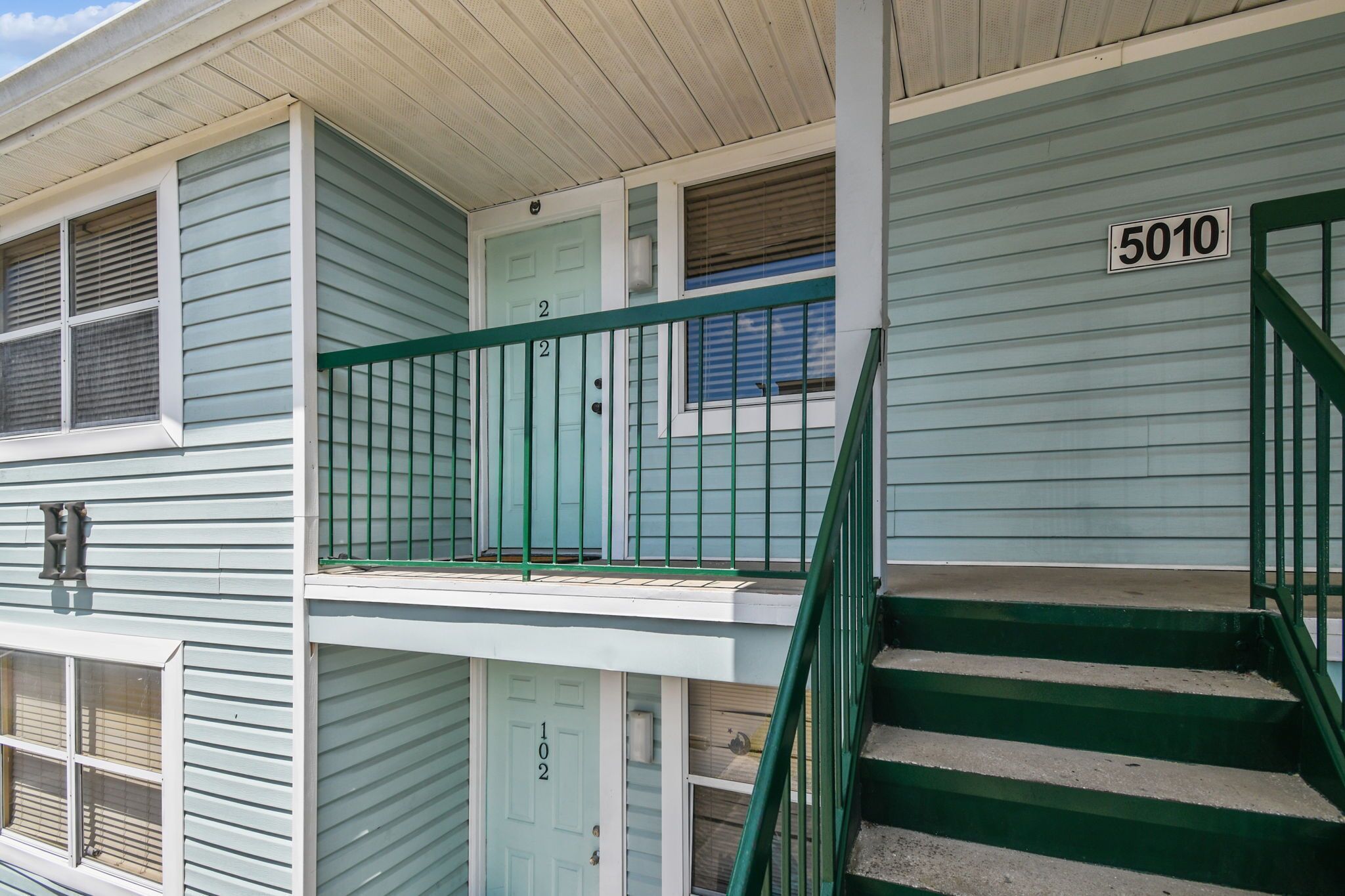 A two-story building with a green staircase and a door marked '5010'.