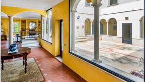 A corridor with yellow walls, white columns, and a view of an outdoor courtyard with arches. - Architectural jewel between sea and mountains (Teià)