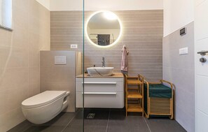 A modern bathroom with a white toilet, a vessel sink, a wooden vanity, a round mirror, and a towel rack. - 3 bedroom beach front apartment in Kastel Novi (Kastel Novi)