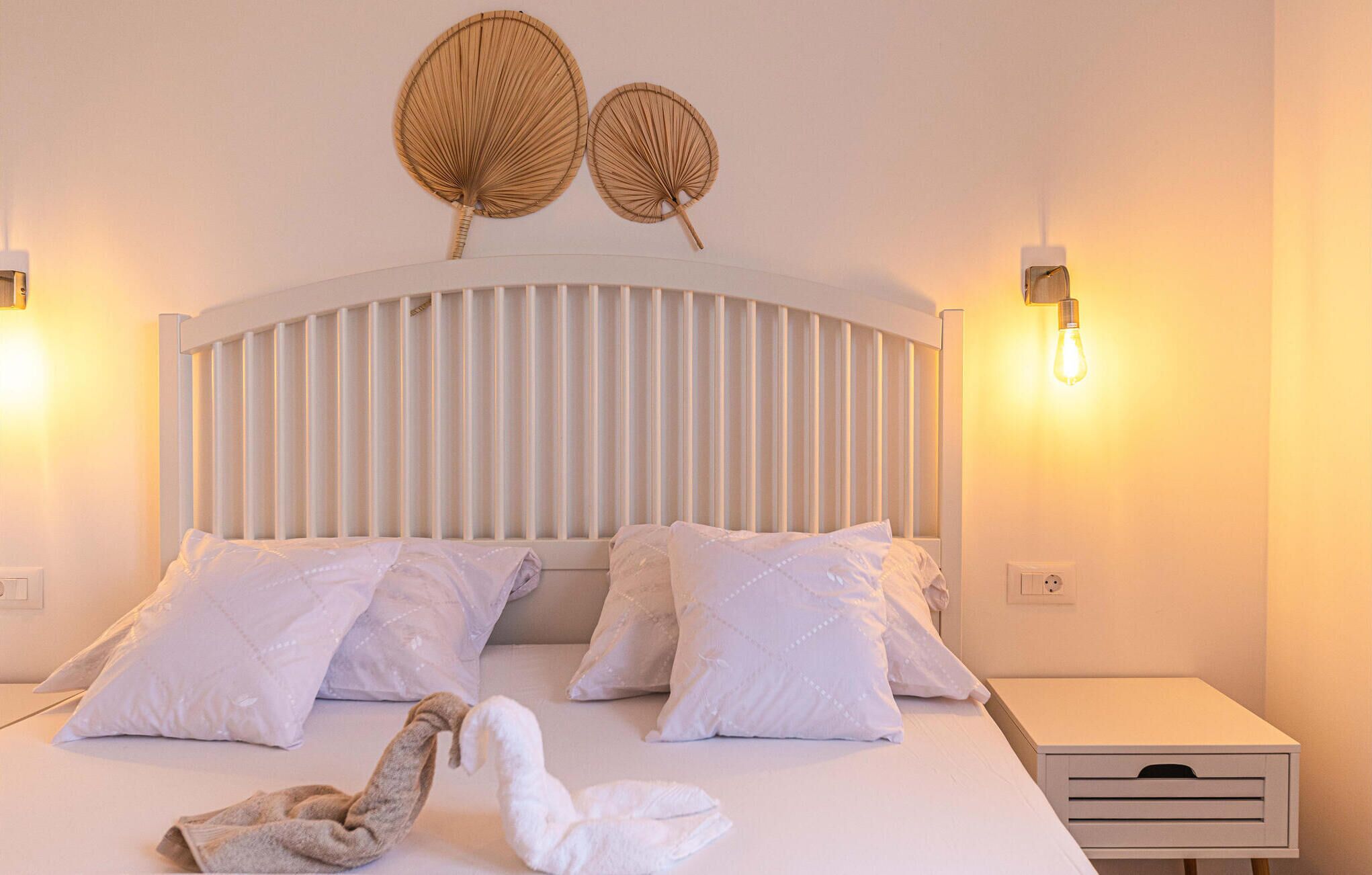 Una habitación de hotel con una cama, dos lámparas de pared y una mesita de noche.