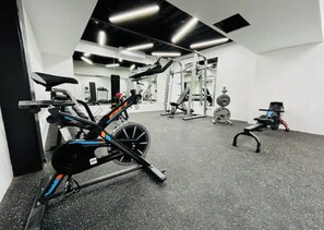 Work out in style with a variety of exercise equipment, including a stationary bike, bench press, and squat rack.