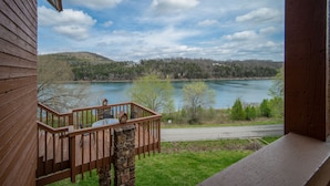 A wooden deck with a stone pillar, overlooking a lake with a forested hillside in the background. - Table Rock Landing Resort (Eureka Springs)