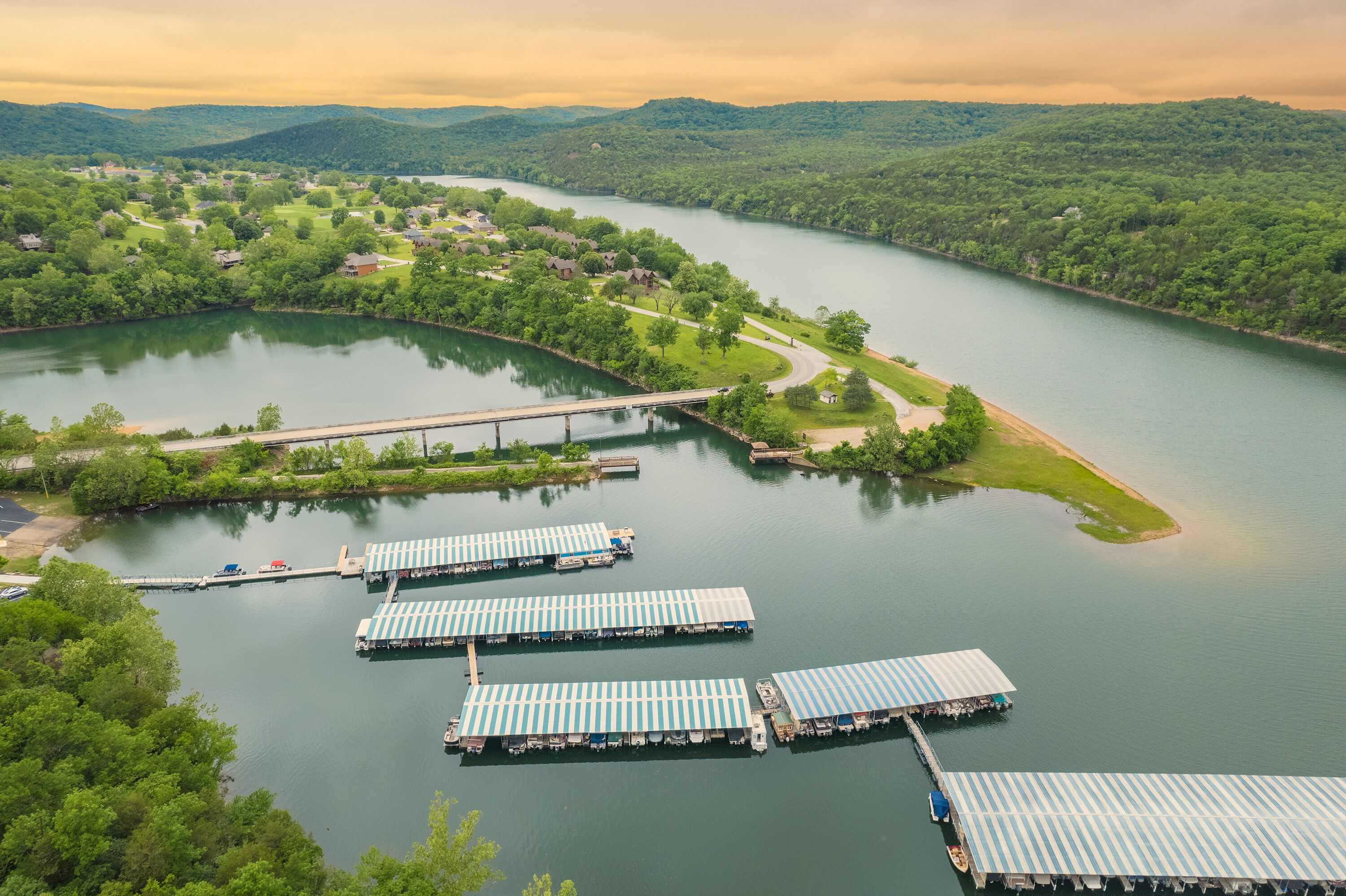 A riverside view with a bridge, docked boats, and a residential area.