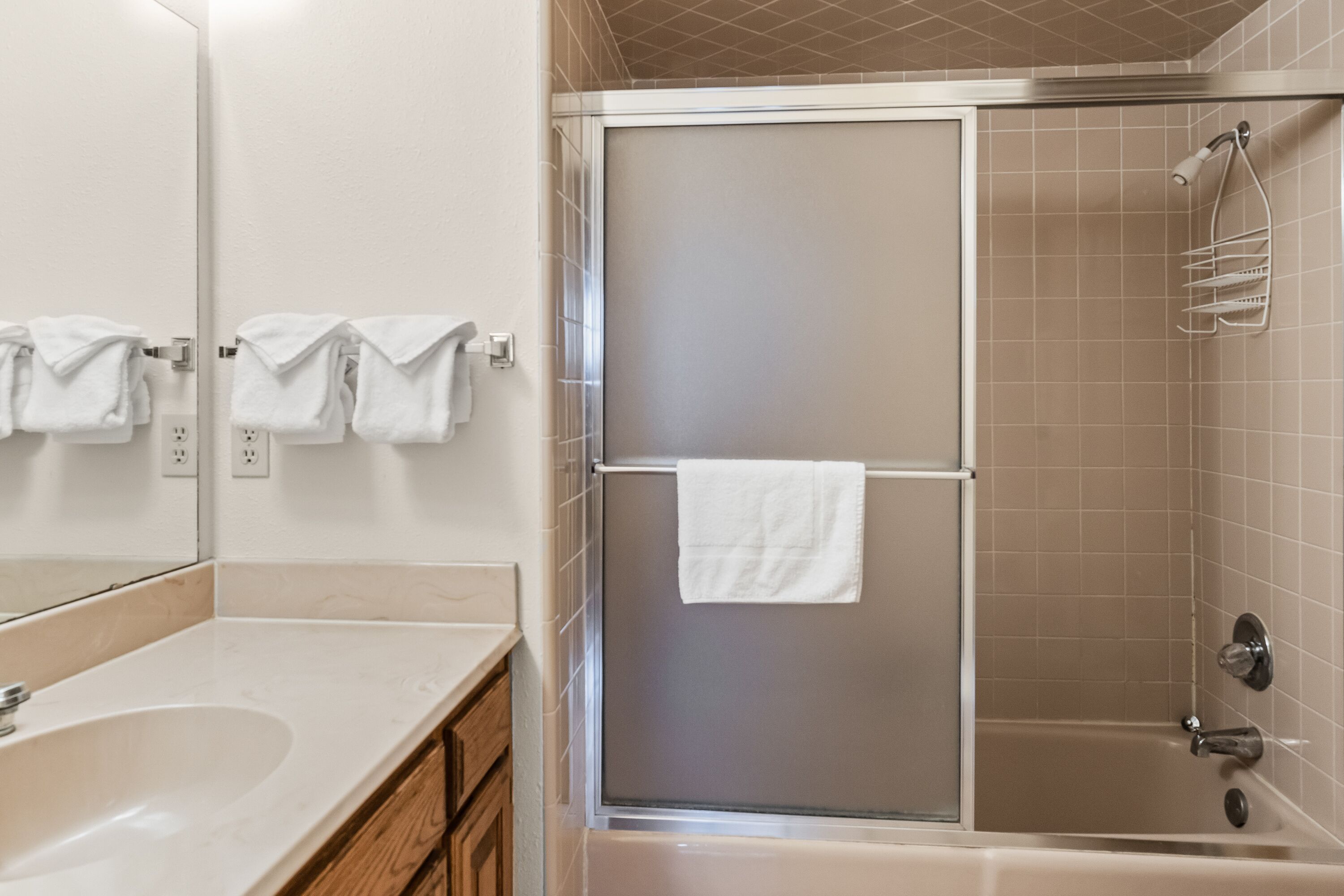 A bathroom with a shower, a sink, and a mirror.