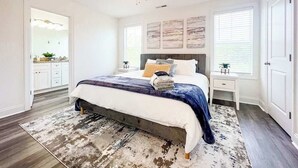 Een slaapkamer met een bed, een plafondventilator, een nachtkastje, een dressoir en een raam met jaloezieën.