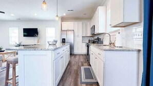 Een moderne keuken met witte kasten, een centraal eiland en hanglampen.