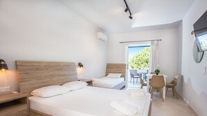 Habitación de hotel moderna con dos camas, un escritorio y un balcón con vistas a zonas verdes.