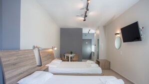 Una habitación de hotel con dos camas, un escritorio, una silla, un televisor y una mesita.