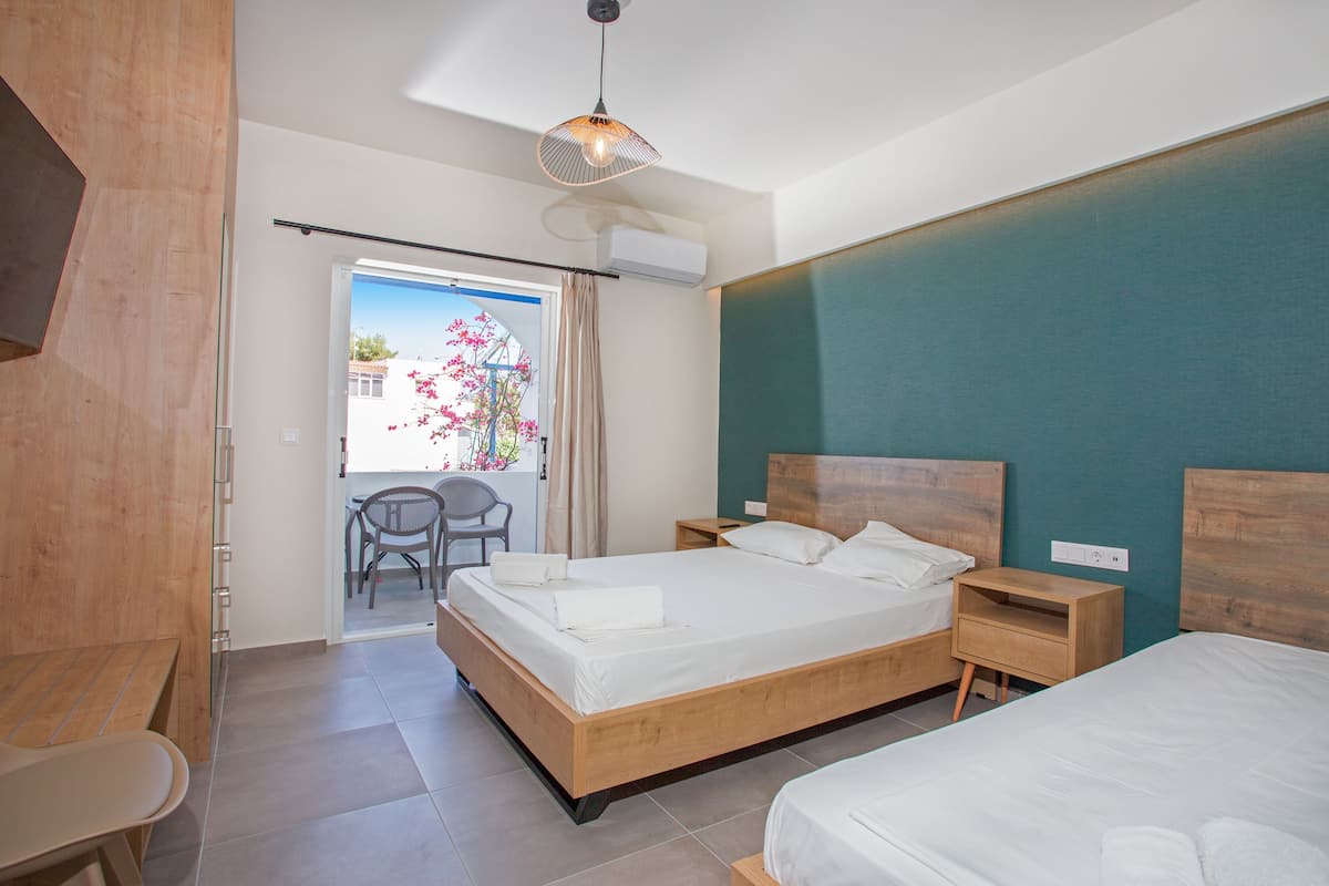 Habitación de hotel con una cama grande, mesitas de noche, un banco de madera y vistas al exterior.