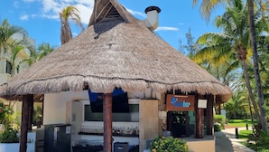 Eine Poolbar mit Strohdach, einem Pool und Palmen.