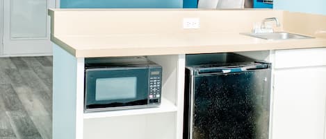 A compact kitchen with a microwave, refrigerator, and sink.