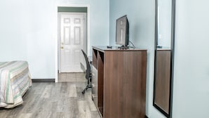 A bedroom with a bed, a desk with a computer, and a door leading to another room. - Captain Quarters Motel (Port O Connor)