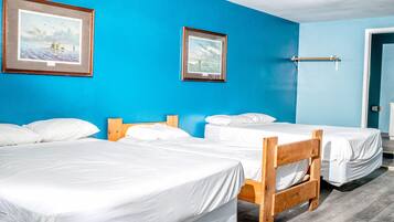 Een hotelkamer met twee enkele bedden, een houten hoofdbord, een blauwe wand en twee ingelijste foto's.