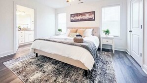 Un dormitorio con cama, ventilador de techo, mesita de noche y ventana.