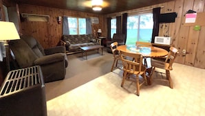 A cozy cabin interior with a living area, a dining table, and a view of the outdoors. - Quiet Northwoods Cabin on Leech Lake, Minnesota (Federal Dam)