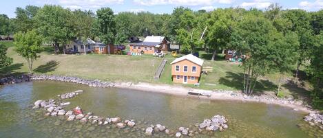 A lakeside property with multiple houses, a dock, and a clear view of the water.