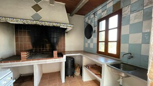 Een kleine keuken met een ingebouwde grill, een raam en een spoelbak.