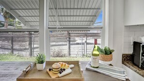 Una cocina con encimera de madera, una botella de vino, una planta y una bandeja con comida.