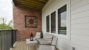 Eine überdachte Veranda mit Backsteinmauer, weißen Fensterläden und einer Uhr in Metallfassung.