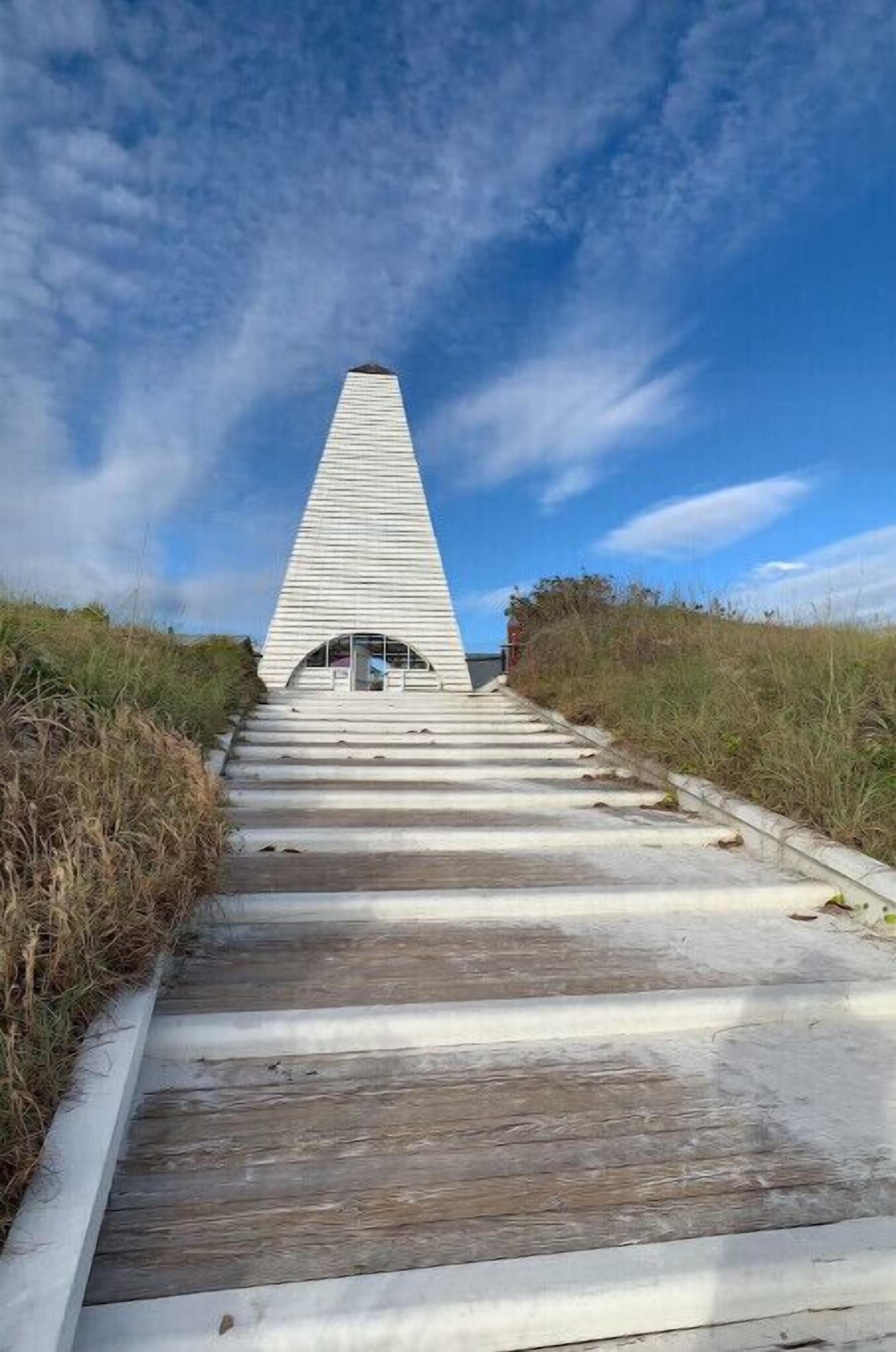 Un sentiero conduce a una struttura bianca a forma di piramide, con un piccolo ingresso.