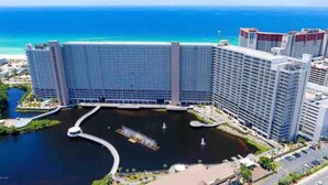 A high-rise hotel with a central courtyard, a marina, and a view of the ocean. - The Lazy Place: Gulf Penthouse, High Ceiling &Bunk (Panama City Beach)