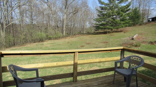 A wooden deck with two plastic chairs and a view of a grassy area with trees. - The 100 Acre Woods located in the Appalachian mountains Clintwood Va (Clintwood)