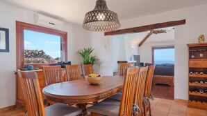 Un comedor con una mesa y sillas de madera, un cuenco de fruta y vistas al exterior.