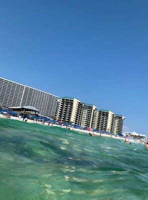 Ein Strandhotel mit mehreren Hochhäusern, einem Sandstrand und klarem, blauem Wasser.