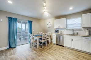 Kitchen area with dining table for four, featuring an oven, stainless steel dishwasher, and sink with faucet and soap dispenser.